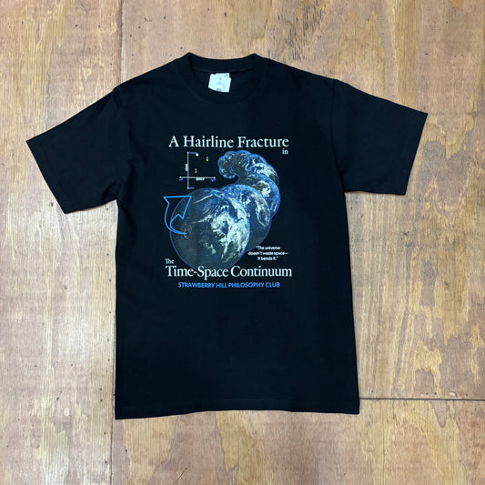 front view of graphic on black -shirt that says 'a hairline fracture in timespace continuum'