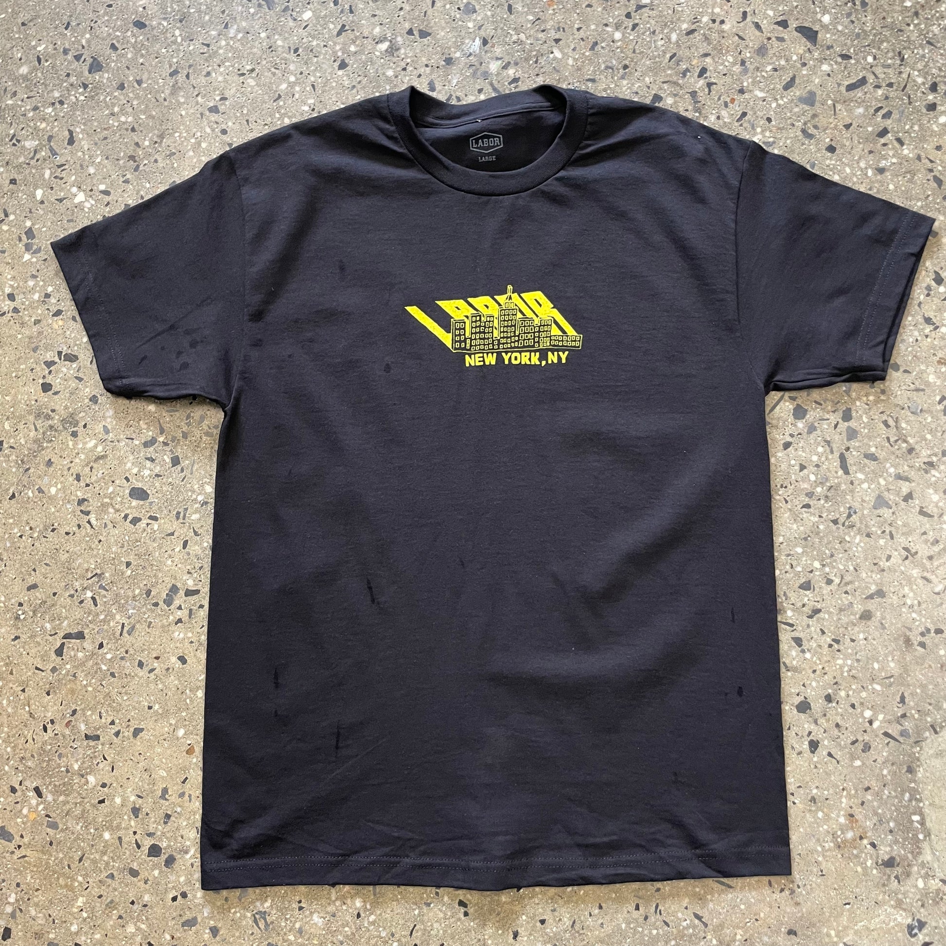 yellow labor cityscape logo printed in center chest of black t-shirt