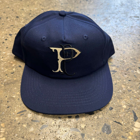 midnight blue hat with cream and black logo