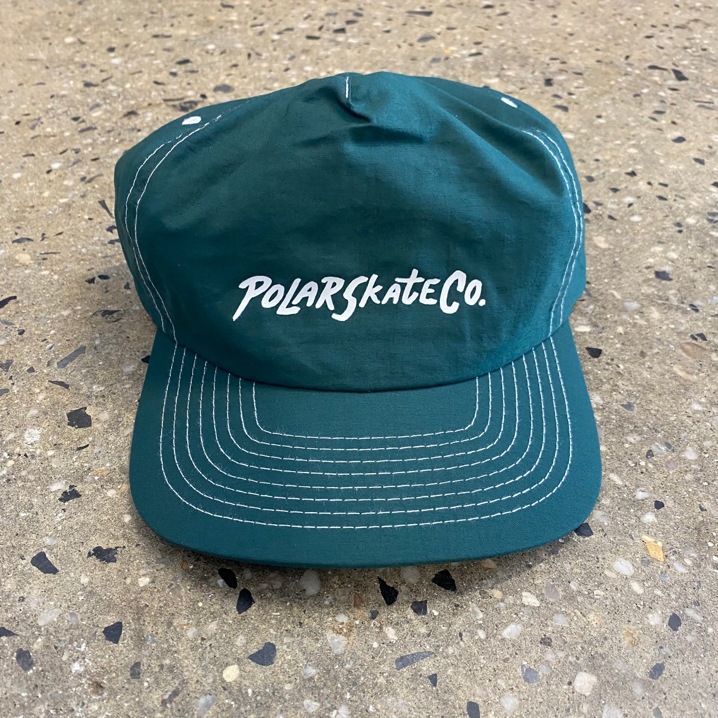 green hat with white stitching and white text in the middle
