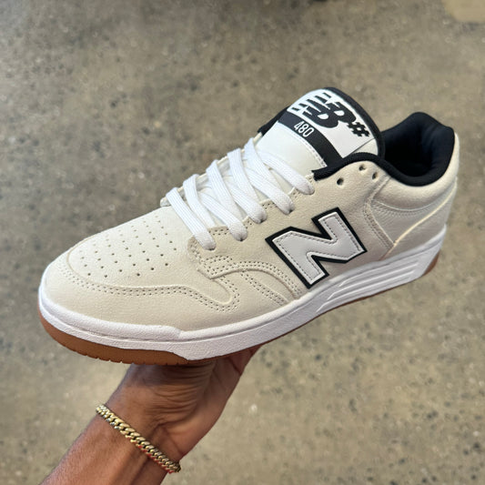 white suede shoe with white logo with a black outline