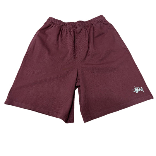 burgundy colored shorts with white stussy logo on the left leg