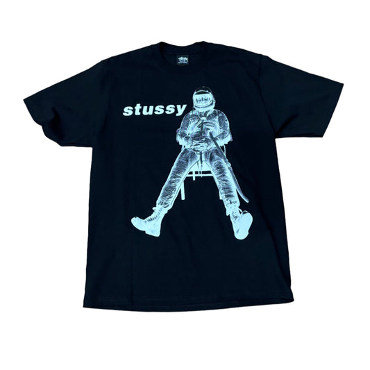 black t-shirt with astronaut sitting in chair with STUSSY above his head