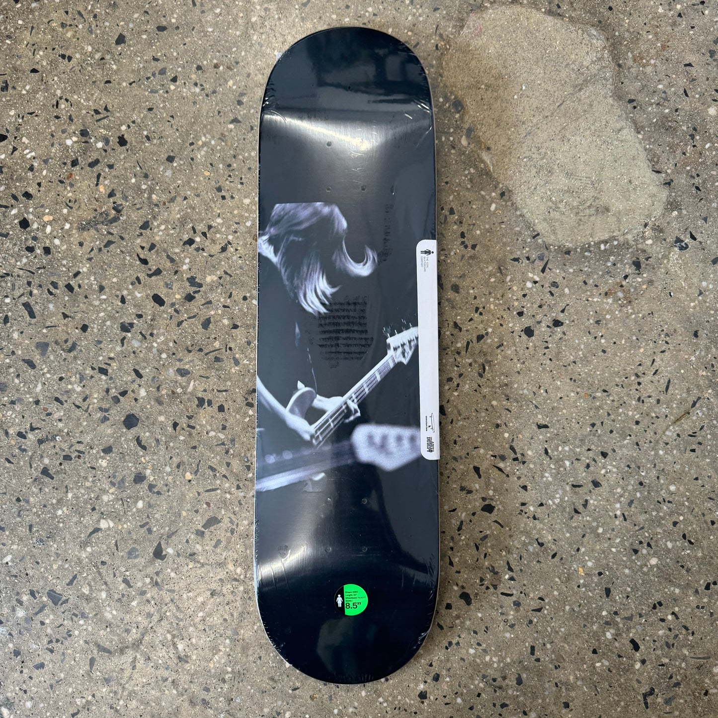 black skate deck with white design of man playing guitar