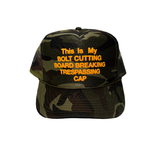 front view of camo trucker cap that reads THIS IS MY BOLT CUTTING BOARD BREAKING TRESPASSING CAP