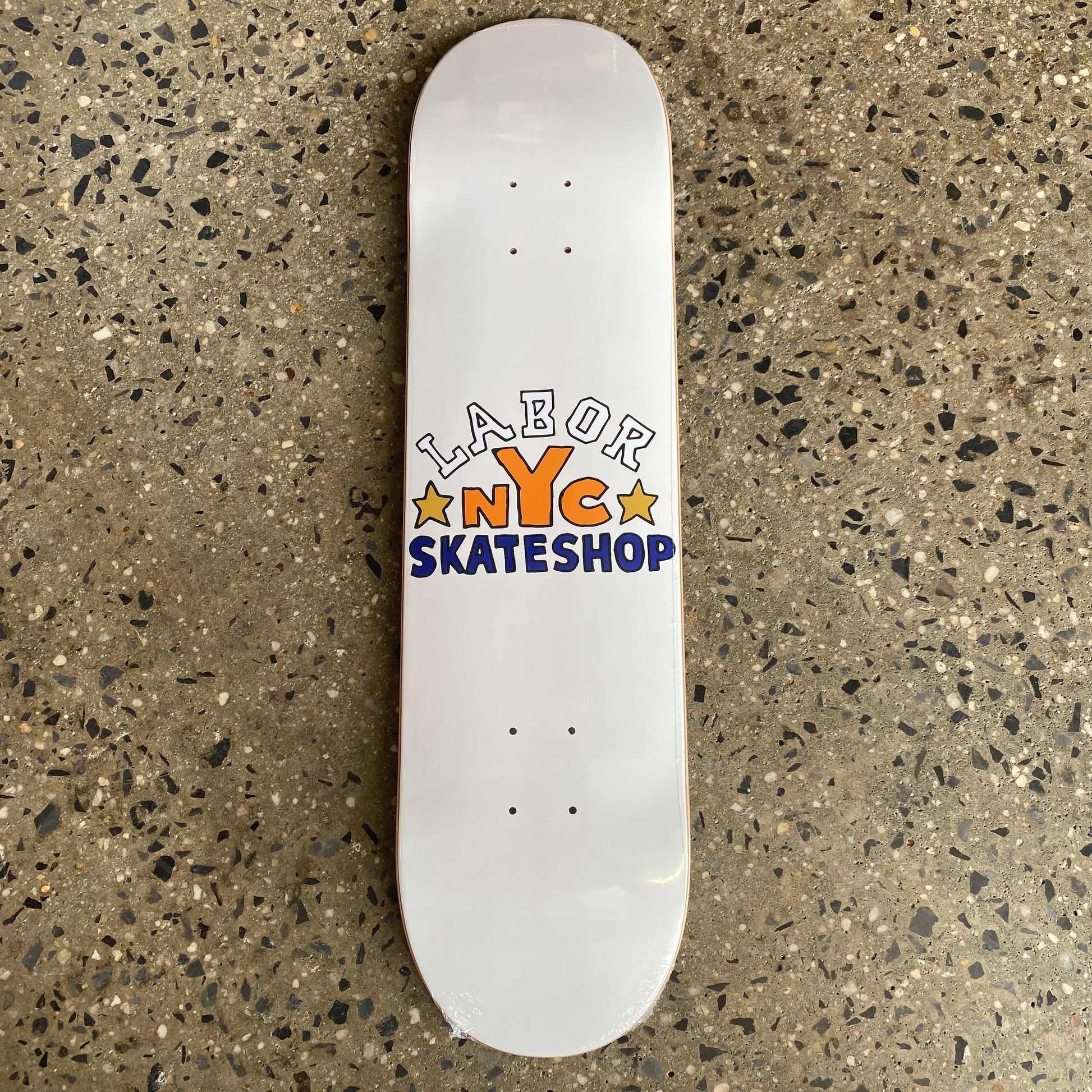 white skateboard with LABOR NYC SKATESHOP written in white orange and blue lettering