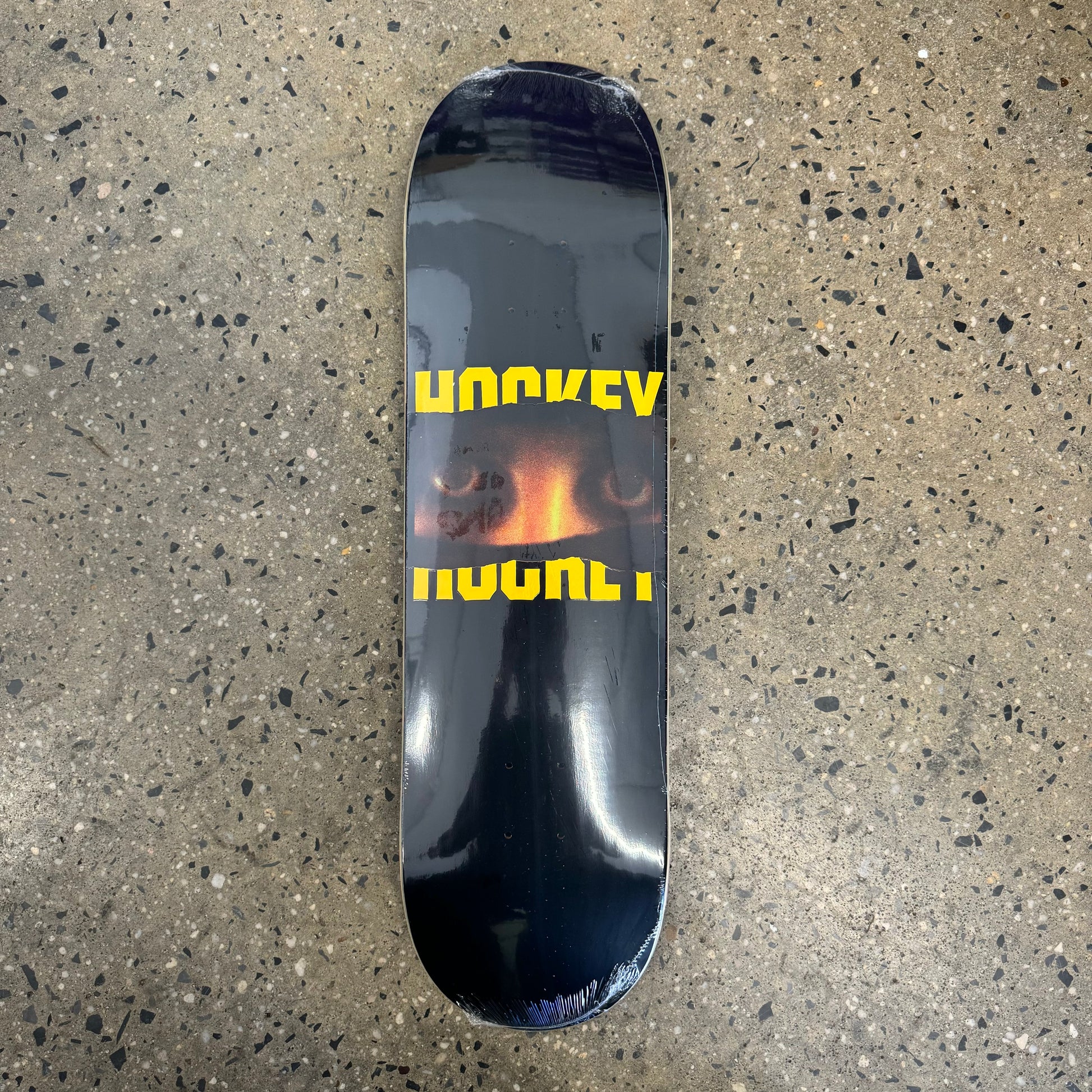 black skateboard deck with yellow text and eyes in the center