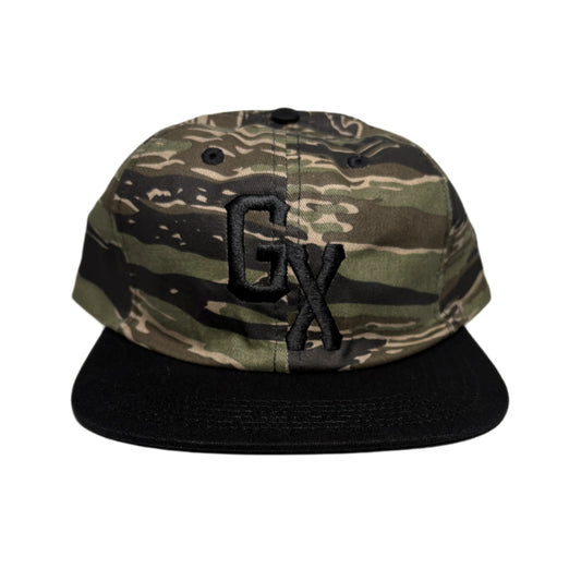 Camouflage-patterned cap with black accents on a white surface