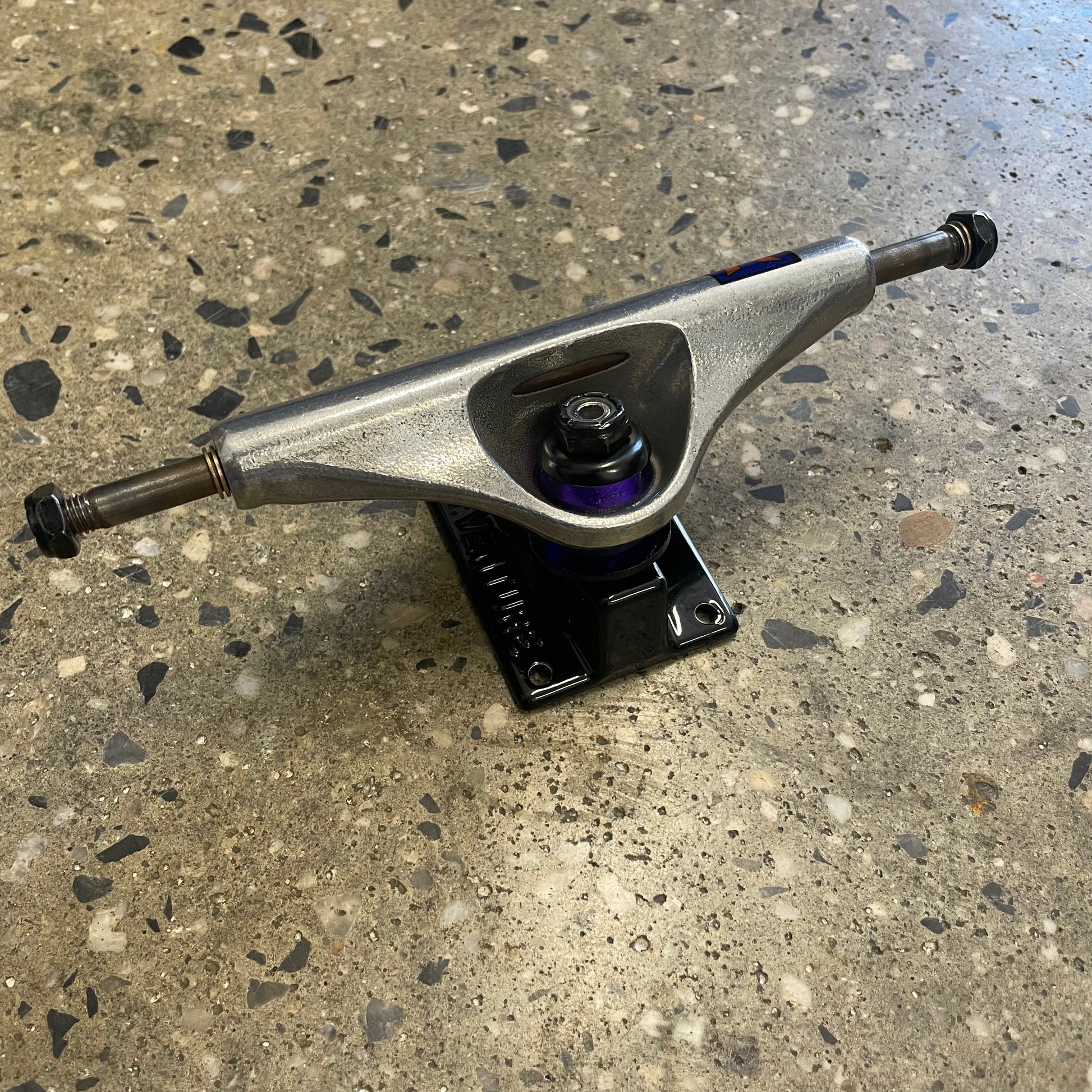 Rear view of silver polished hanger and black baseplate truck, purple bushings