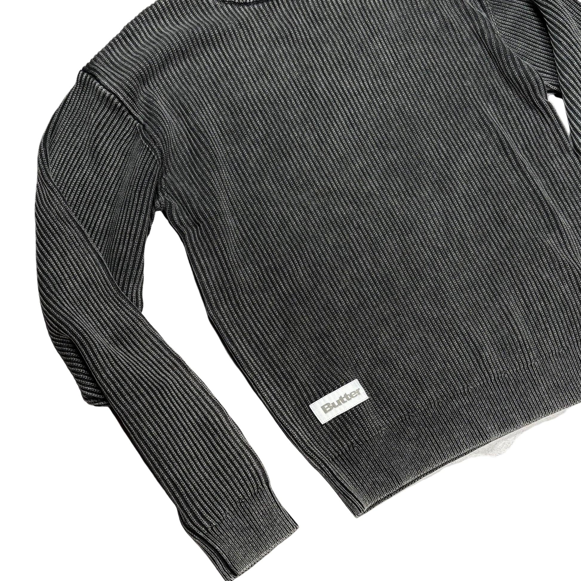 Gray ribbed sweater with a butter brand label on a white surface.