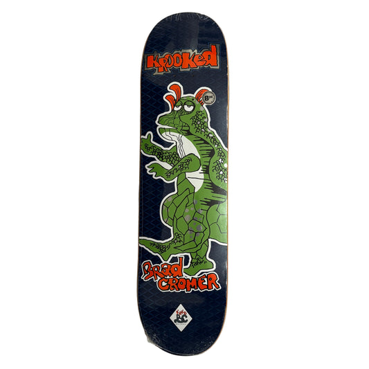 Skateboard deck with a green dragon design and krooked branding on a white surface