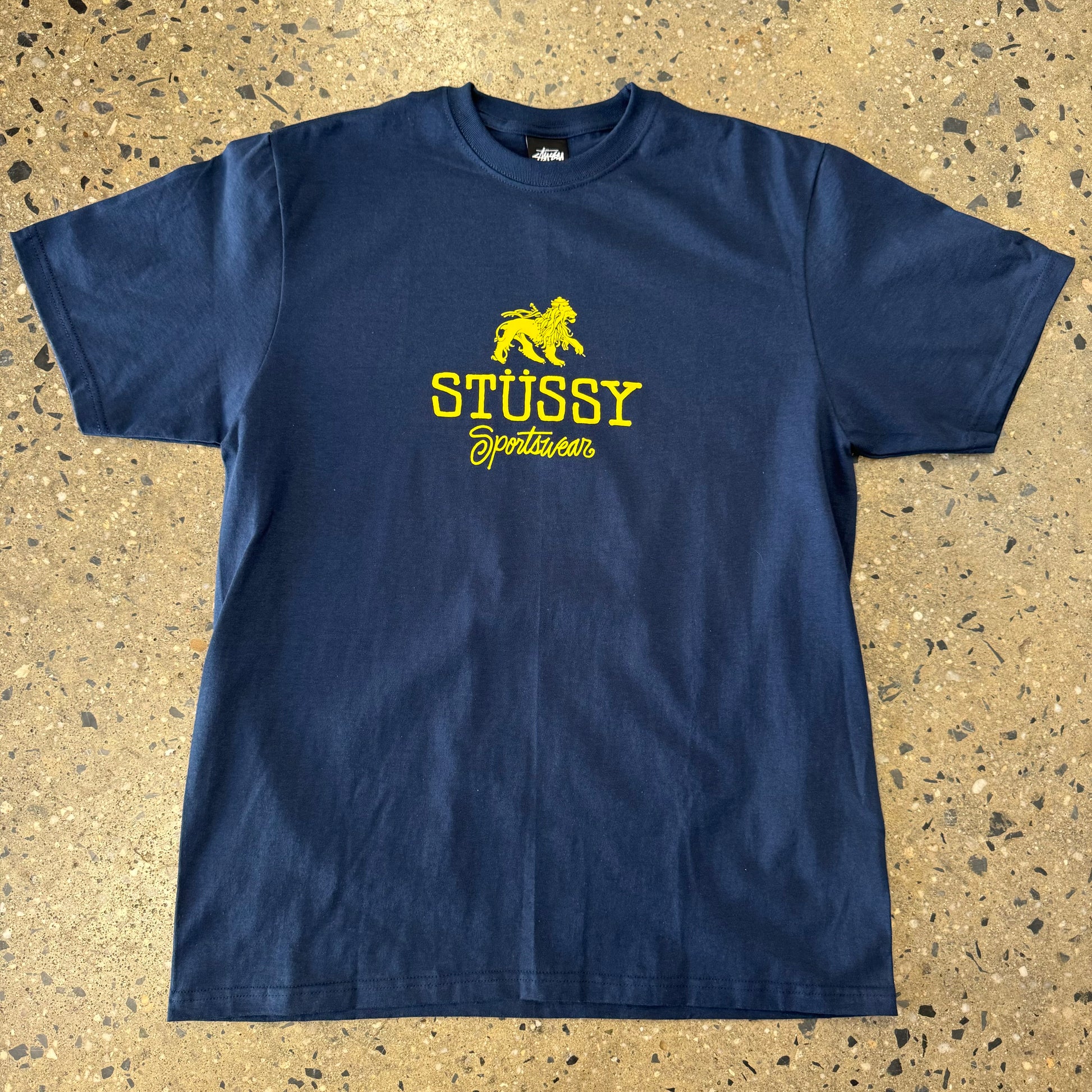 front view of navy stussy t-shirt with stussy sportswear written under a lion