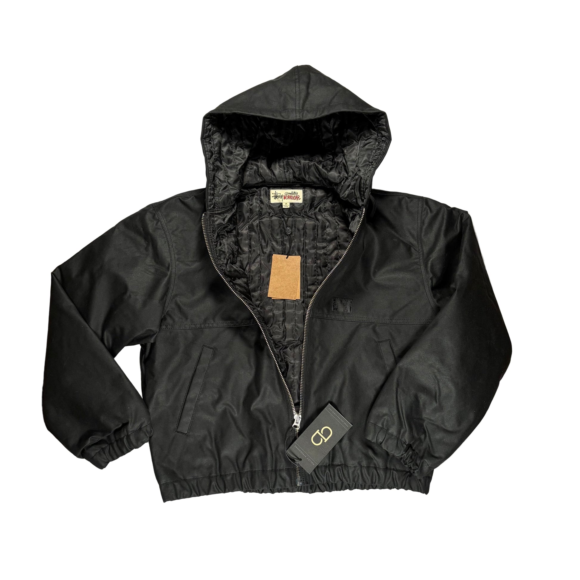 Black waxed work jacket , unzipped, with a brand tag on a white surface