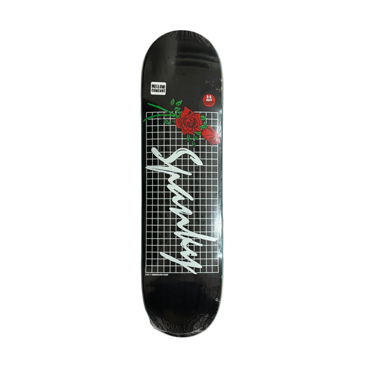 Skateboard deck with a black background, white text, and red rose design on a white surface.