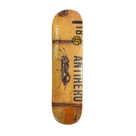 Skateboard deck with ant graphic and text on a white surface