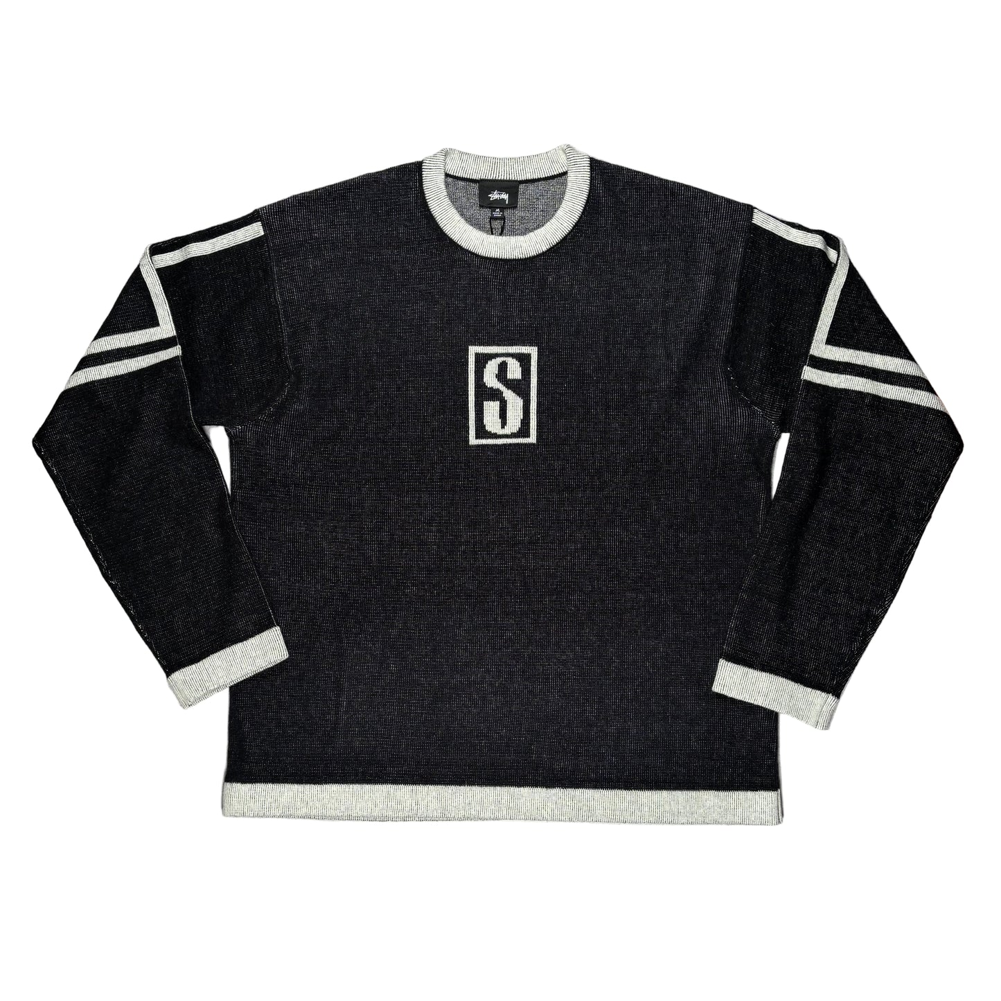 Black sweater with white trim and a logo on a white surface