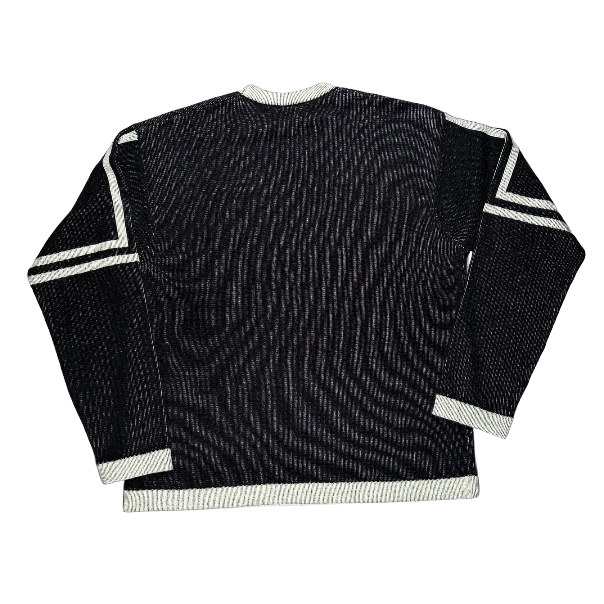 Black sweater with white trim on a white surface