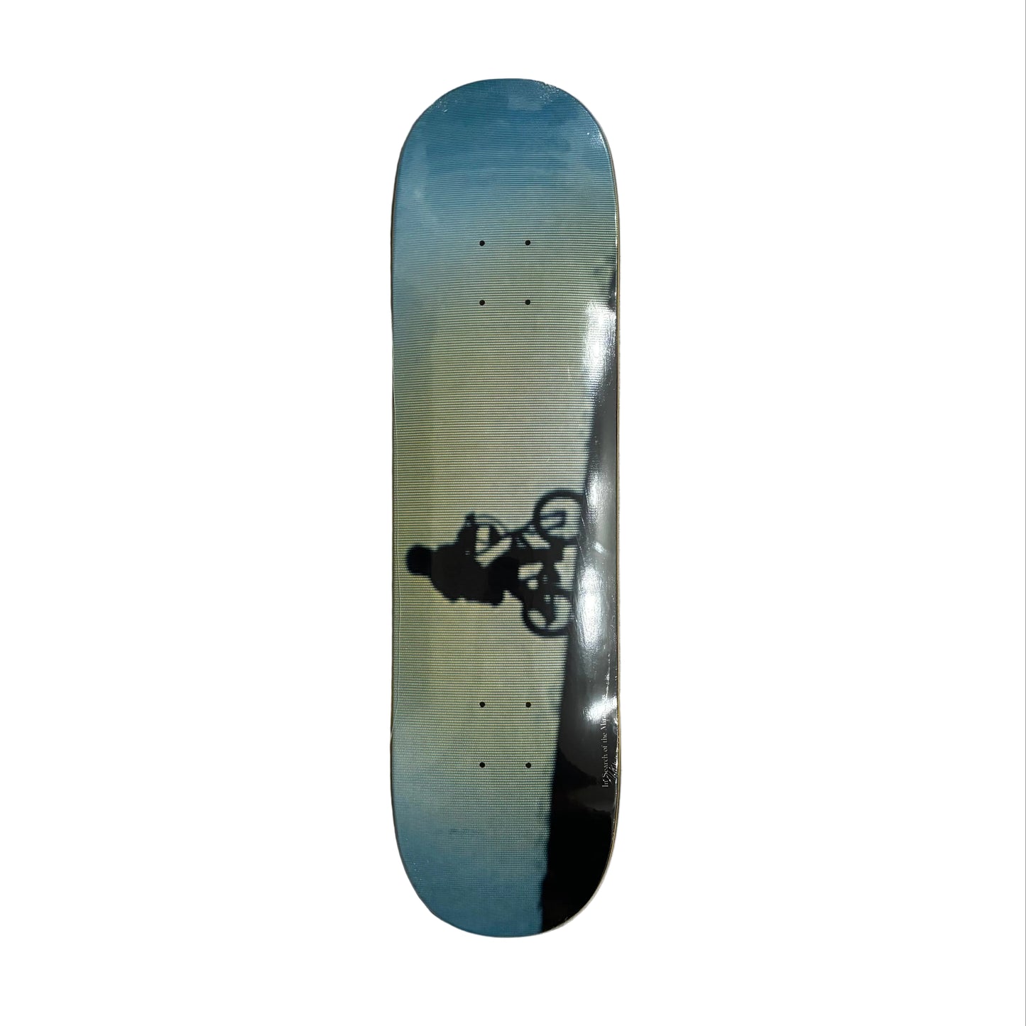 Skateboard deck with a gradient design and a graphic of a person on a bike on a white surface.