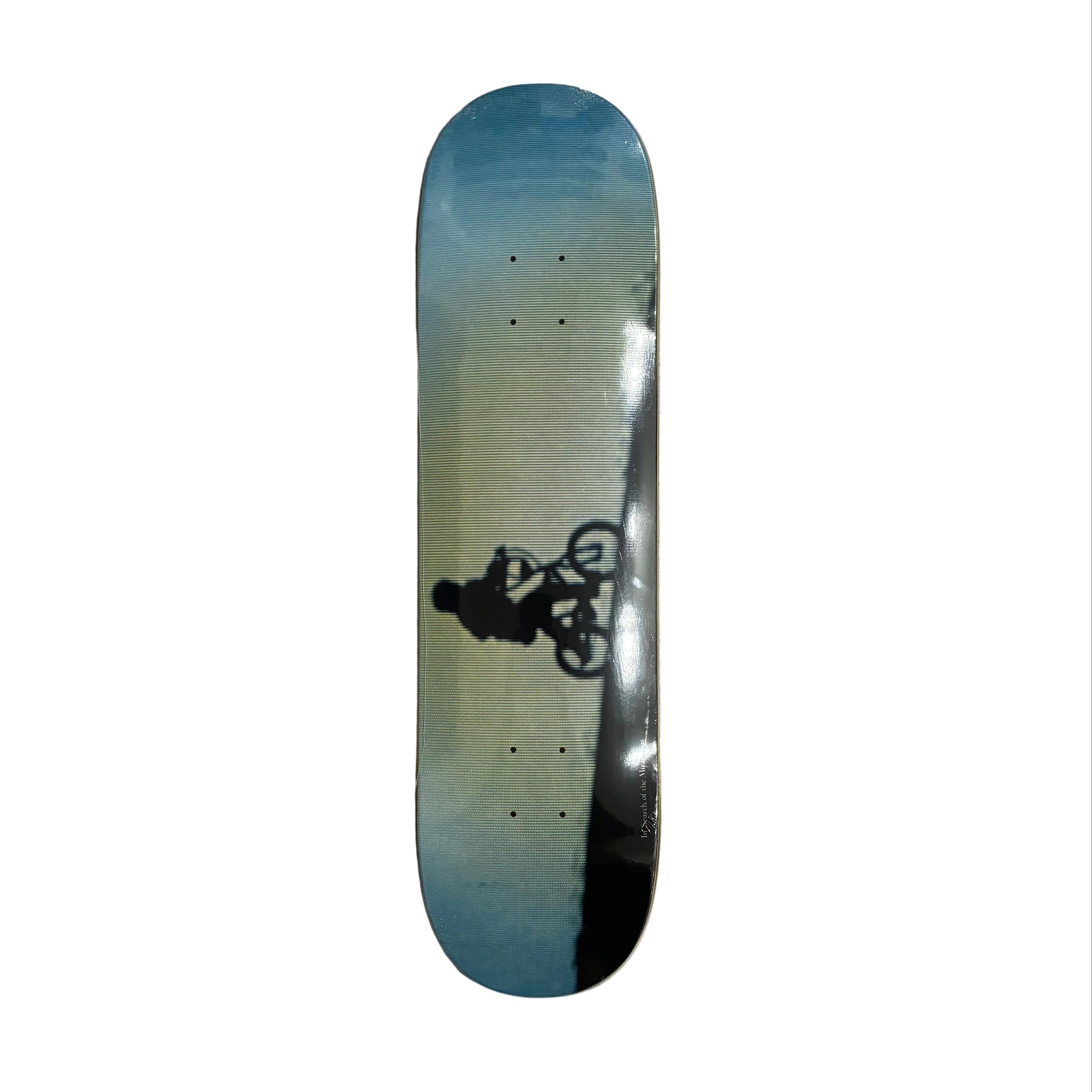Skateboard deck with a gradient design and a graphic of a person on a bike on a white surface.