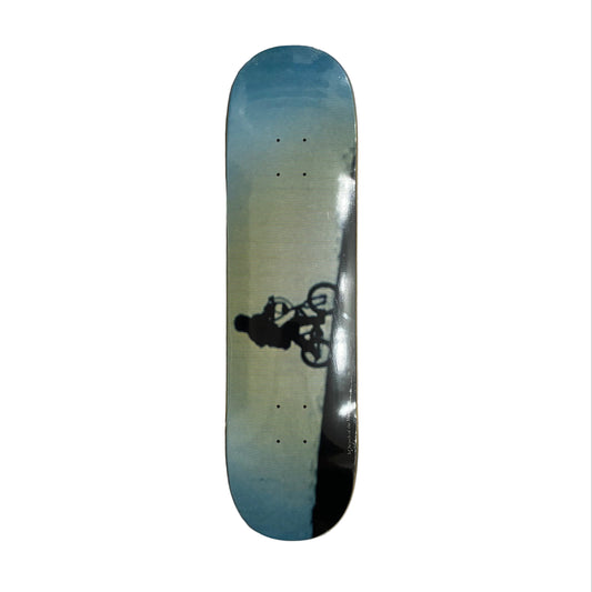 Skateboard deck with a gradient design and a graphic of a person on a bike on a white surface.
