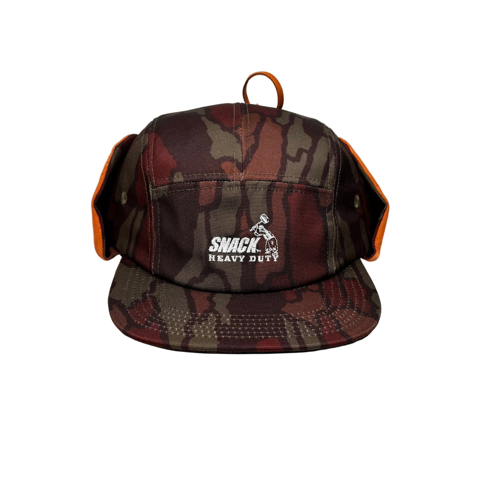 Camouflage-patterned ear flap cap with 'Snack Heavy Duty' logo on a white pedestal  background