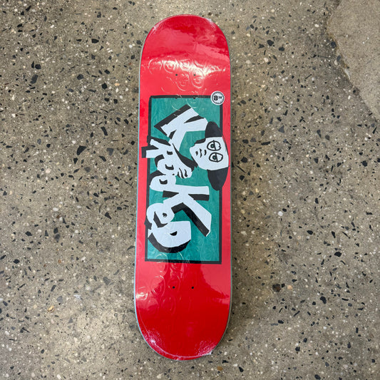 white and black Krooked logo with face on green background, red skate deck
