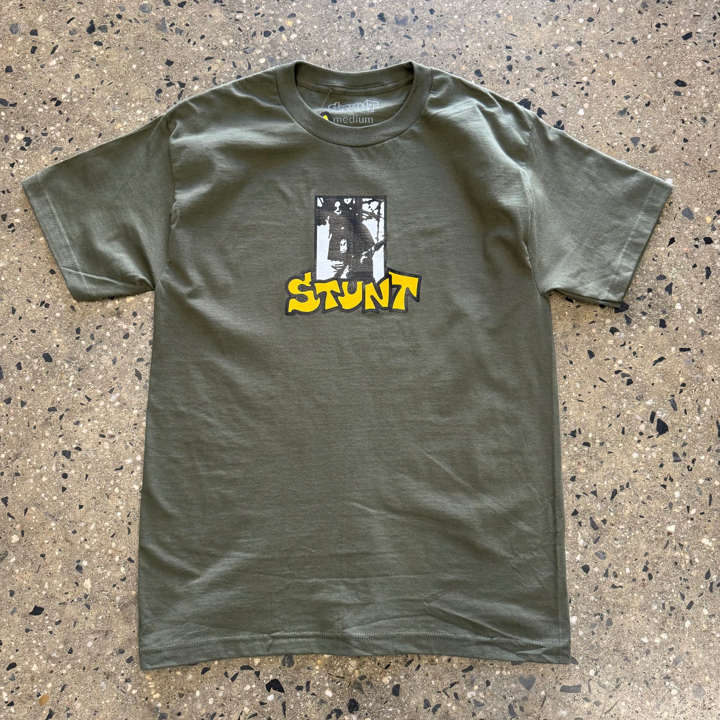 Black white and yellow guitar player logo on army green t-shirt