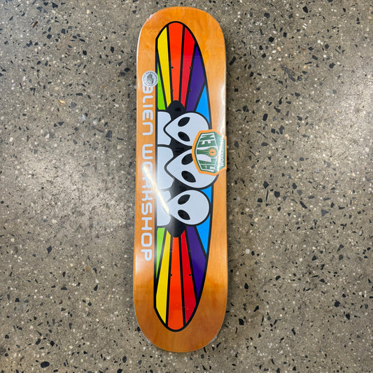 Three alien heads with rainbow spectrum logo behind them, stained woodgrain background, colors may vary, on skate deck