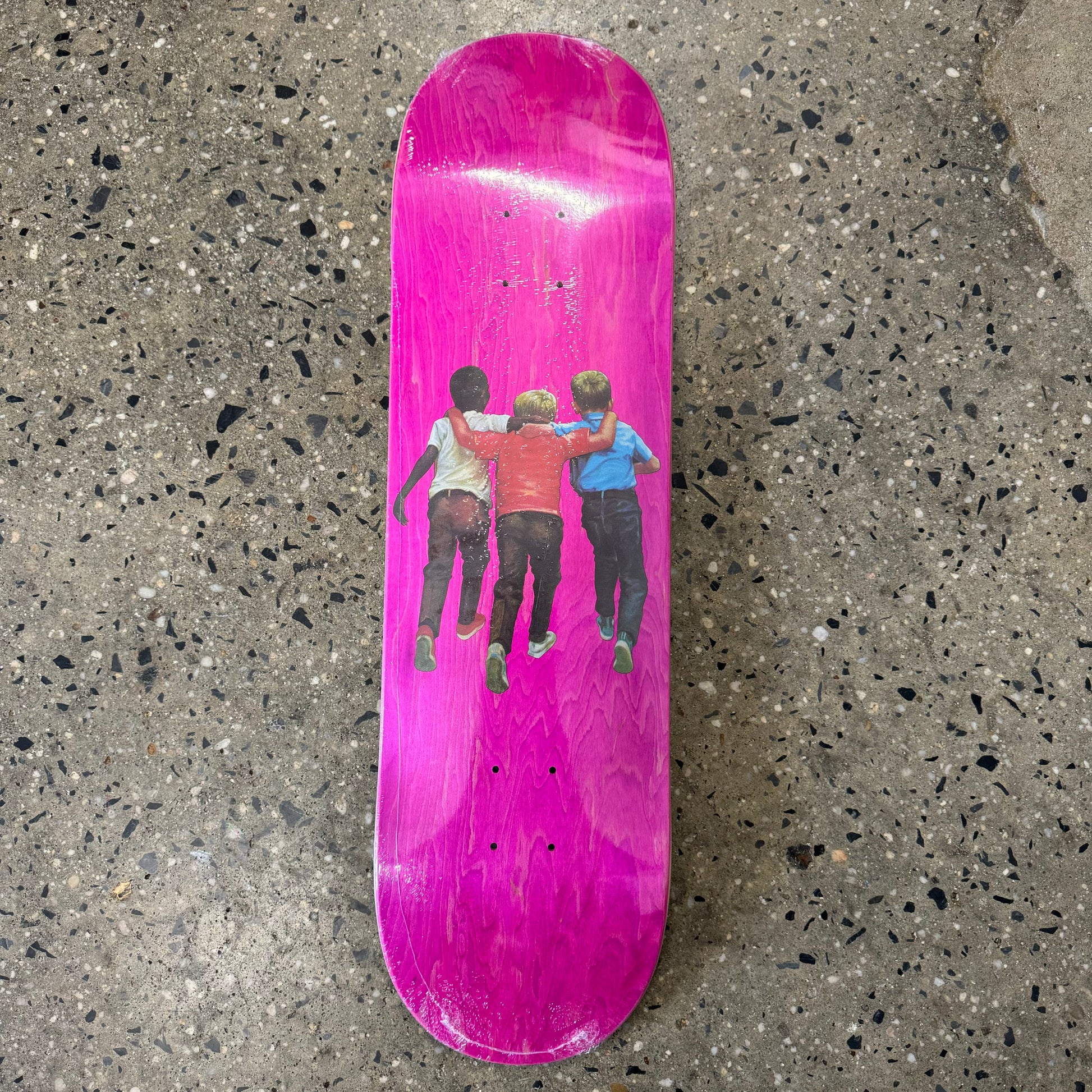 3 kids with arms around each other on pink skate deck