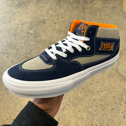 Side view of navy and light grey suede and canvas skateboard shoe with orange accents and white outsole