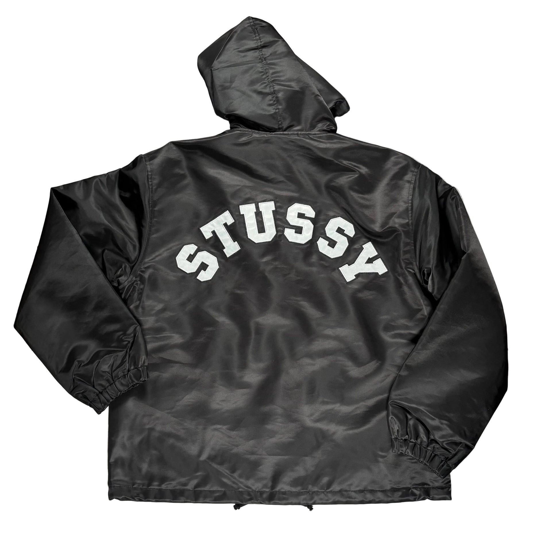 Black jacket with 'Stussy' branding on a white surface