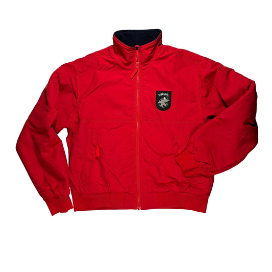Red jacket with a stussy logo on a white surface