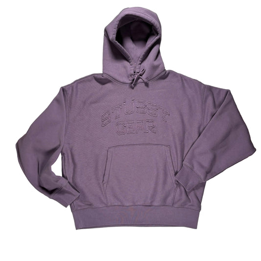 Purple hoodie with 'Stussy Gear' text on a white surface