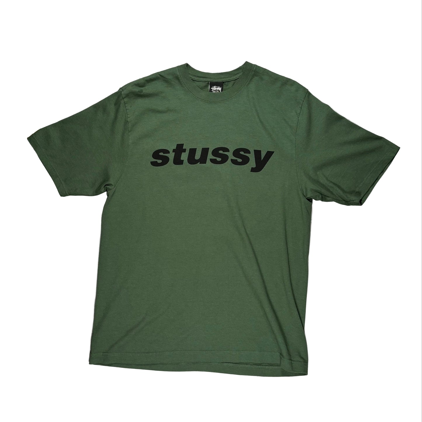 Green t-shirt with 'stussy' logo on a white surface