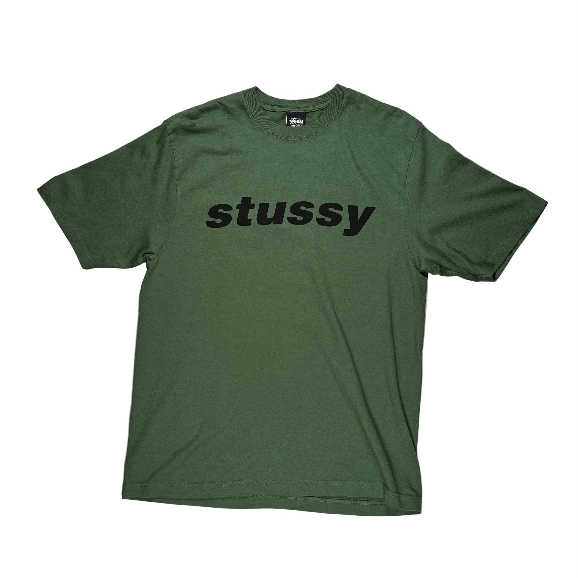 Green t-shirt with 'stussy' logo on a white surface