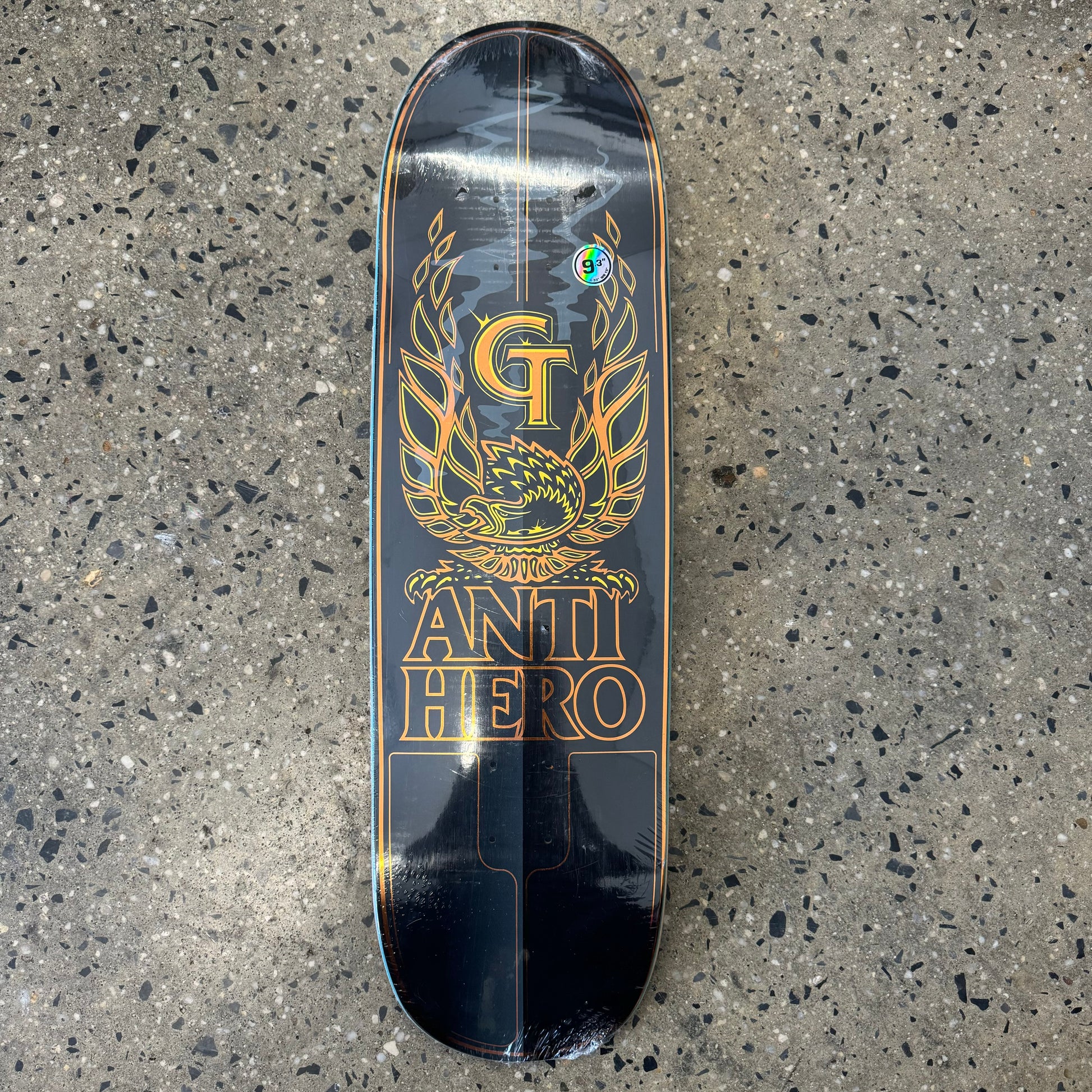 Yellow and gold GT logo with eagle and stacked anti hero logo, on black skate deck