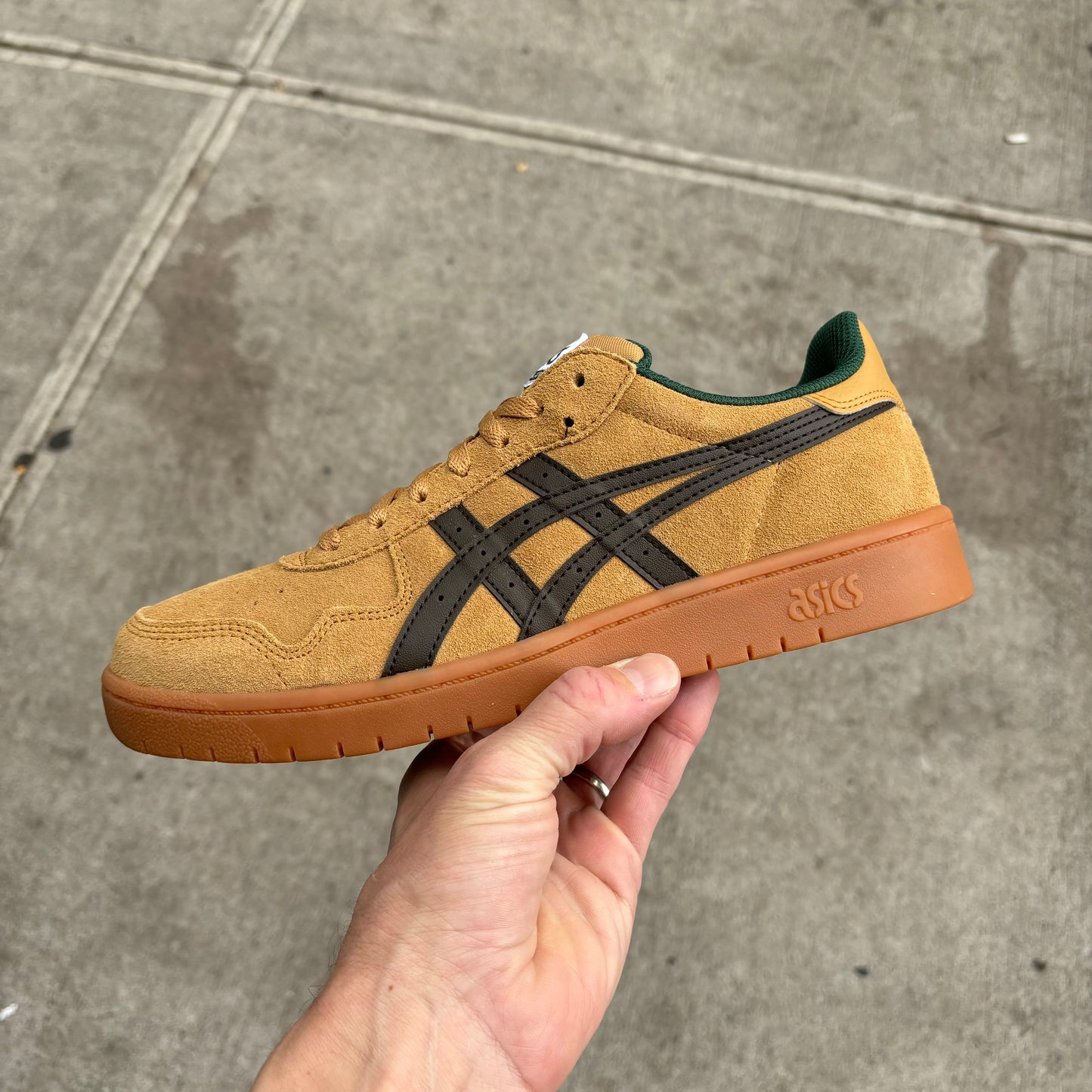 Side view of light brown suede skate sneaker with black and green accents