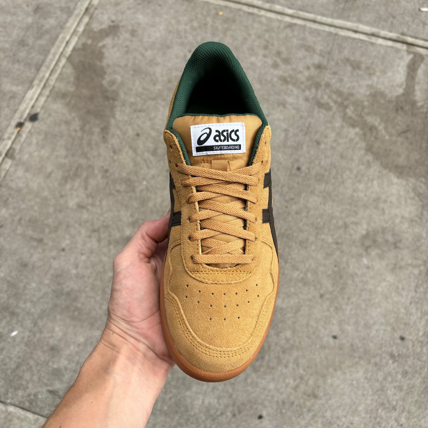 Top down view of light brown suede skate sneaker with black and green accents