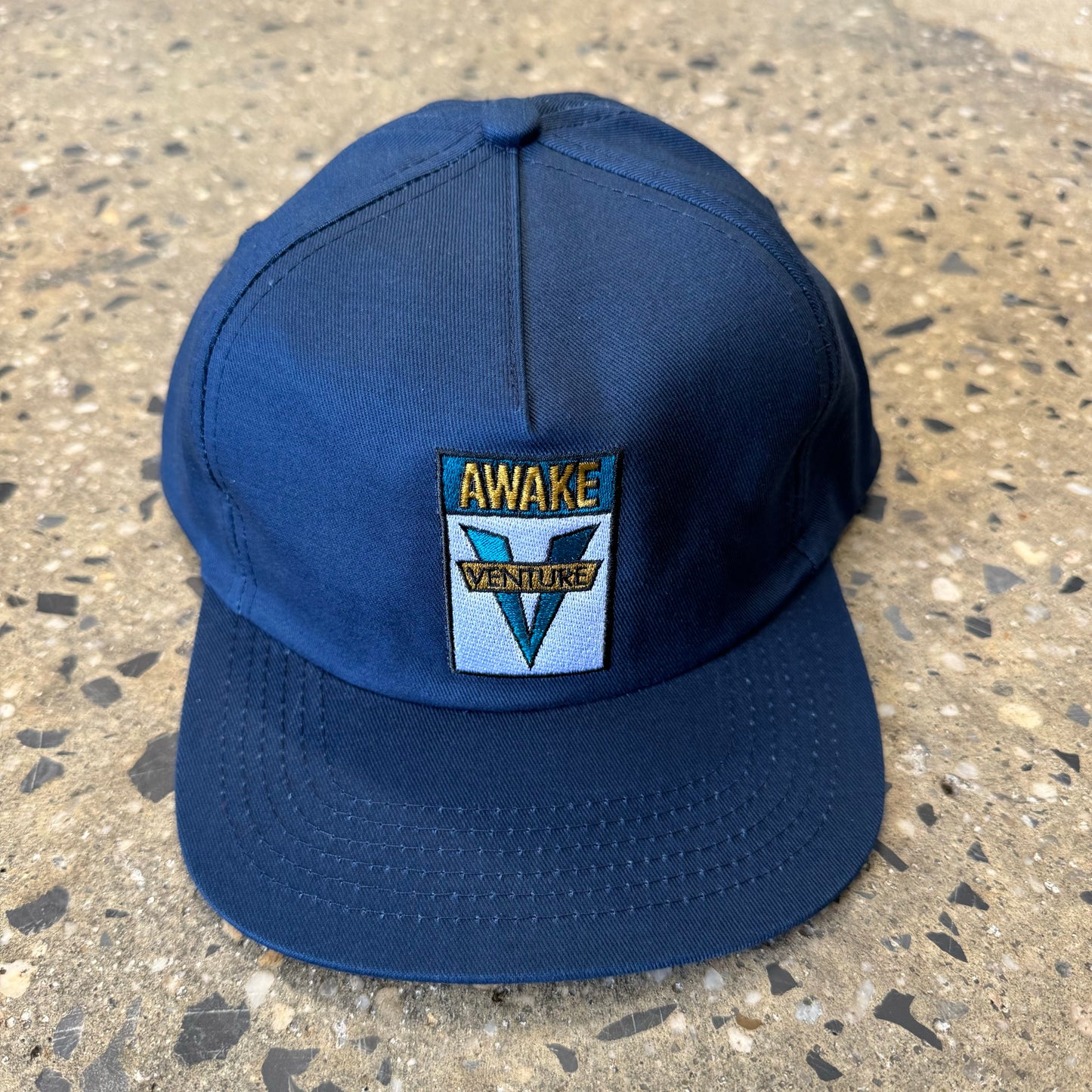 navy hat with venture logo in teal/yellow text in the center of the hat