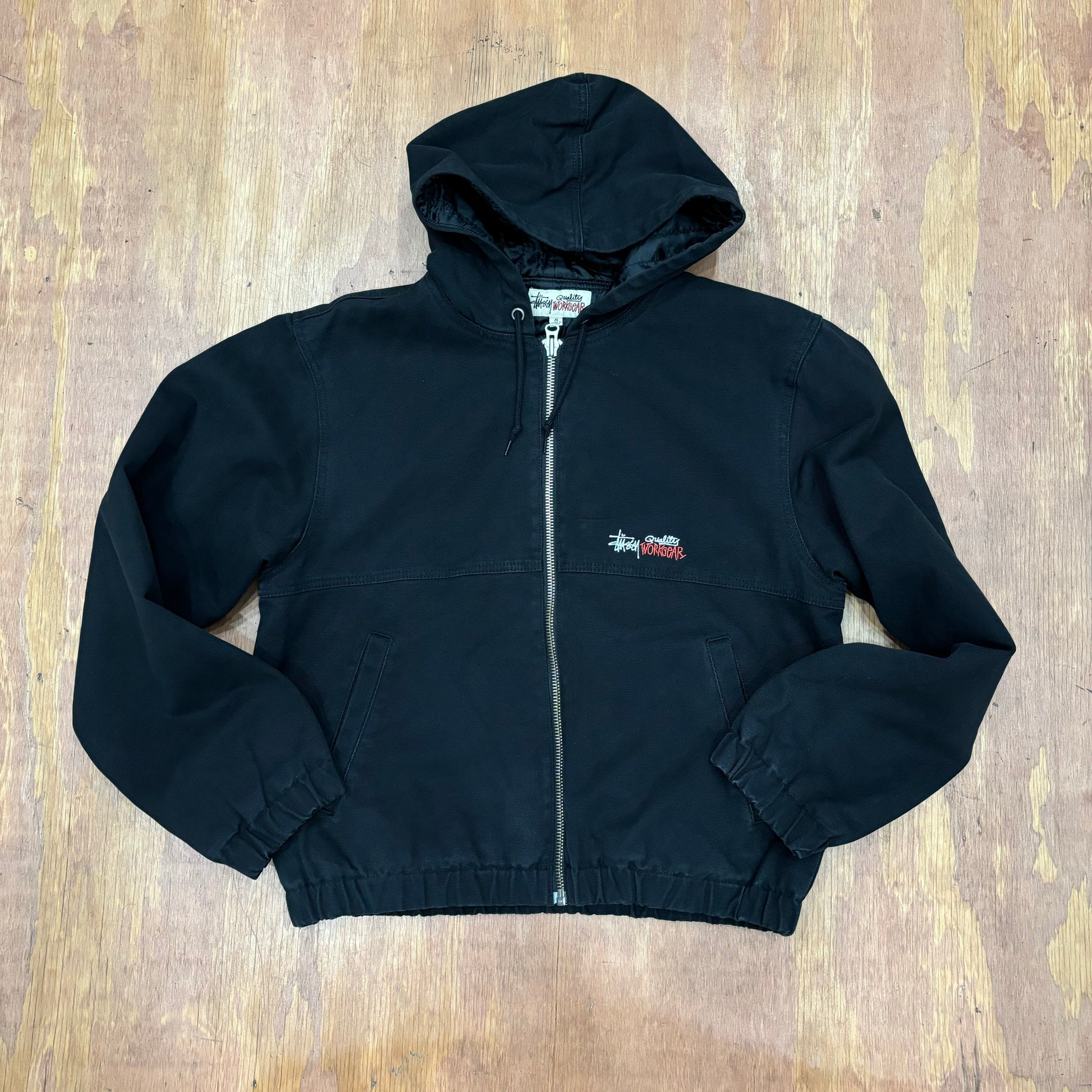 Front view of stussy hooded work jacket in black