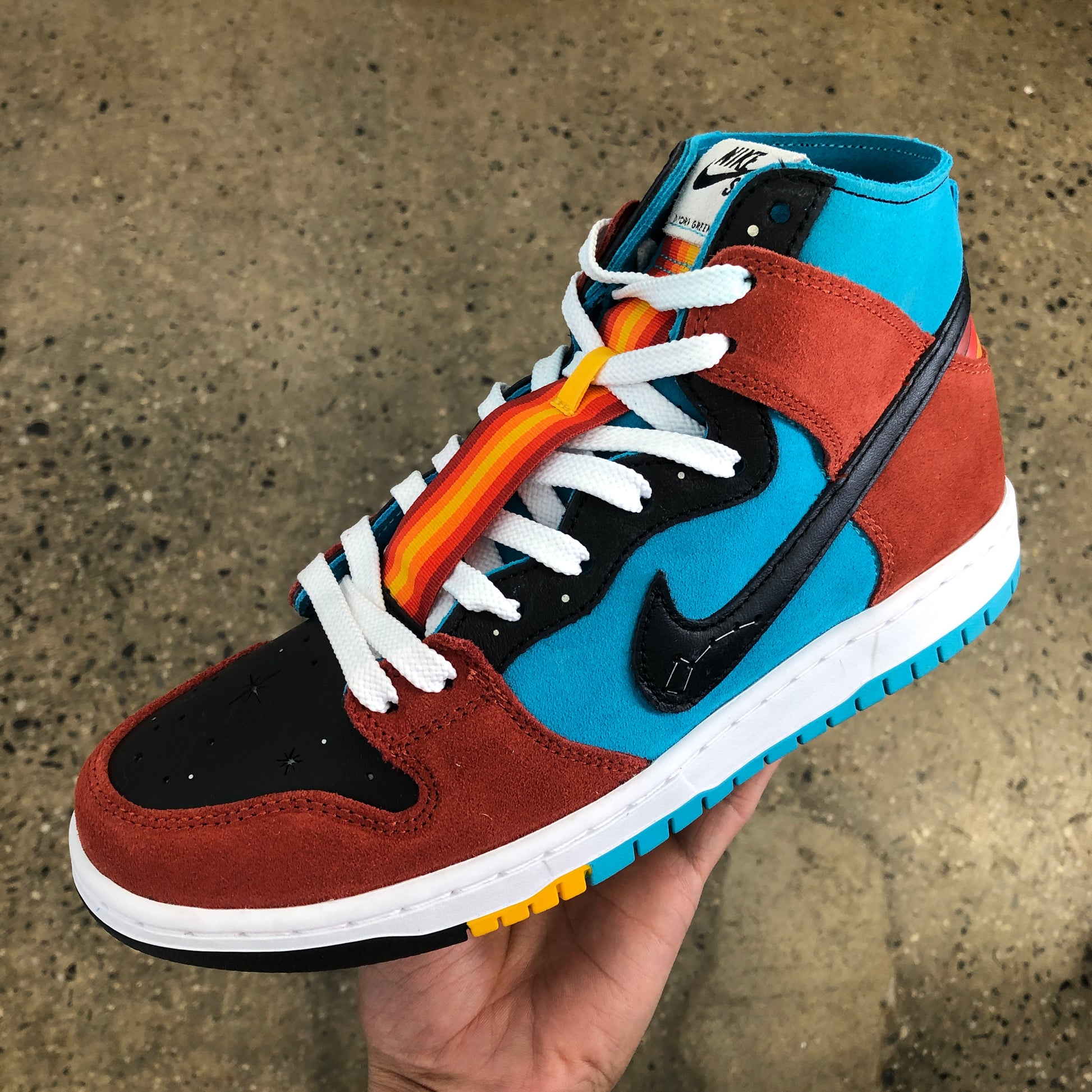 photo of a shoe with red and blue panels, a black nike swoosh, and white laces with a colorful lace protector