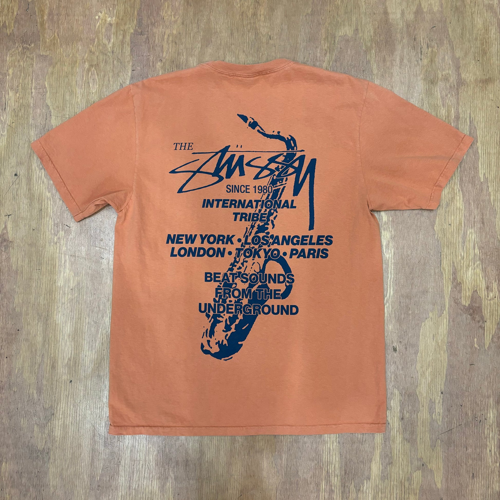 View of rear of stussy graphic tee with saxophone and text