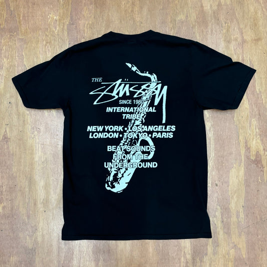 View of rear of stussy graphic tee with saxophone and text
