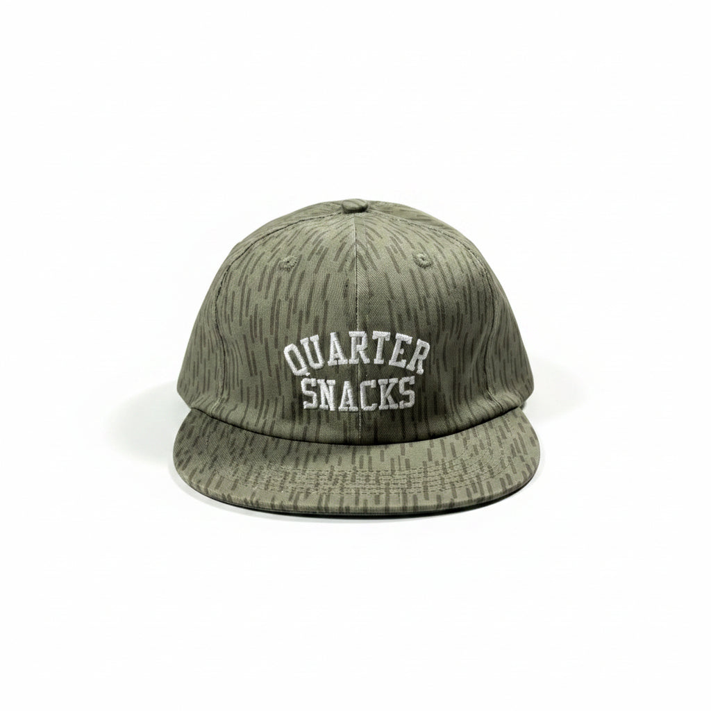 Green cap with 'Quarter Snacks' text on a white surface