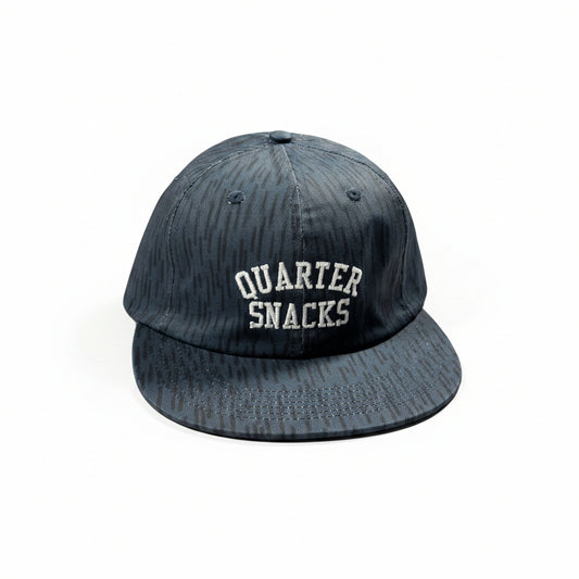 Black cap with 'Quarter Snacks' text on a white surface