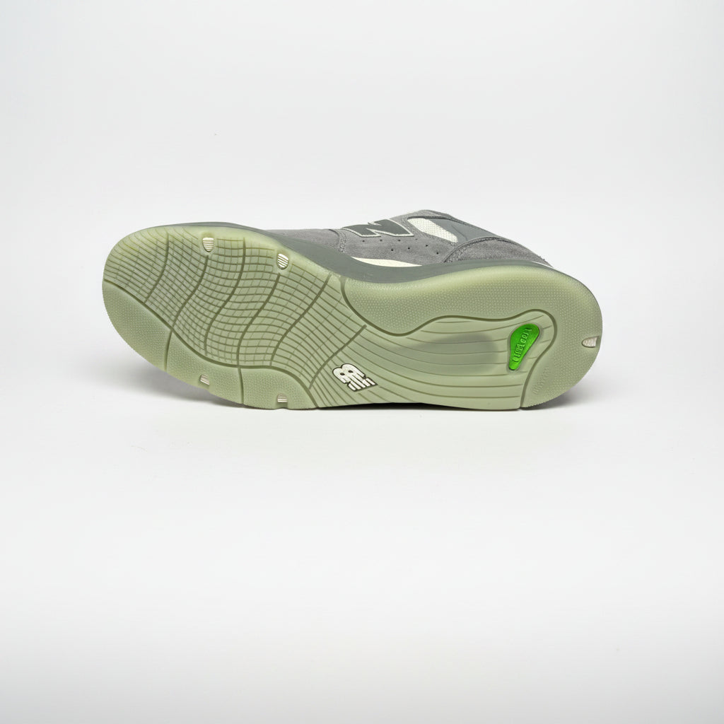Gray sneaker with green sole on a white background