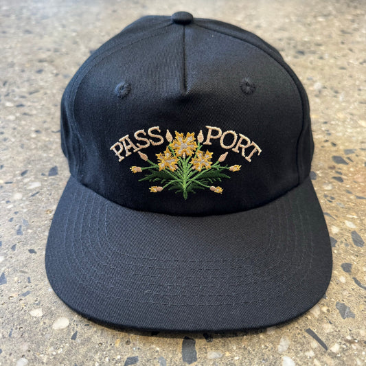 black snapback hat with white text and flowers in the center