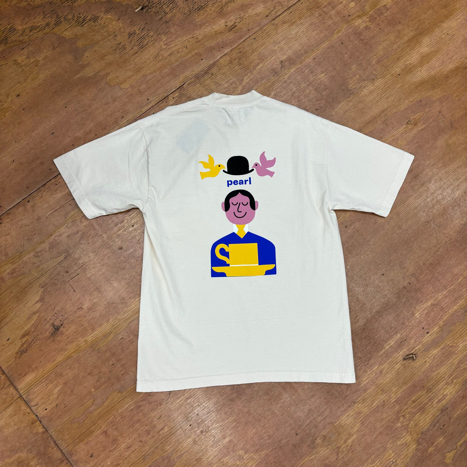 view of back of tee with graphic on back of man, hat, and doves