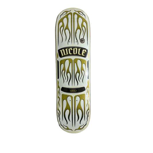Skateboard deck with gold and black flame design on a gray wall.