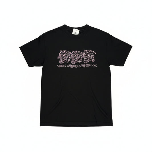 Black t-shirt with three pink hand drawn cat logos on center chest of tee, tee on a white surface